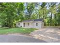 Inviting single-story home with a gray exterior, a covered front porch, and a spacious driveway, surrounded by mature trees at 4410 Burgin St, Kannapolis, NC 28081