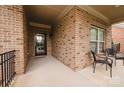 Inviting covered porch with brick columns, seating area, and stylish front door at 4518 Courtyard Blvd # 4, Harrisburg, NC 28075