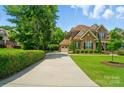 Long driveway leads to a beautiful stone and brick home with an attached garage and manicured landscaping at 463 Langston Place Dr, Fort Mill, SC 29708