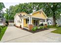 Spacious yellow home with a welcoming front porch, long drive way, and lush landscaped grounds at 660 Ideal Way, Charlotte, NC 28203