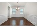 Formal dining room with hardwood floors, elegant chandelier, and wainscoting, perfect for hosting dinner parties at 9285 Swimming Dr, Harrisburg, NC 28075