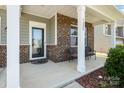 Inviting front porch with brick accents, columns, and seating area perfect for relaxing and enjoying the outdoors at 9285 Swimming Dr, Harrisburg, NC 28075