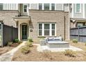 Close-up of a townhome's entrance with a gray patio set, brick facade, and a welcoming green door at 10022 Wayfair Meadow Ct, Charlotte, NC 28277