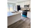 Well-lit kitchen with white cabinets, stainless steel appliances, a kitchen island, and modern flooring at 1012 4Th St, Statesville, NC 28677