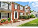 Brick townhome with manicured landscaping, sidewalk, and covered porch at 10867 Garden Oaks Ln, Charlotte, NC 28273