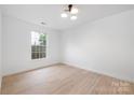 Bright bedroom featuring neutral paint, hardwood floors, a modern ceiling light, and a large window at 12013 Dolomite Dr, Pineville, NC 28134