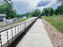 Long driveway leading to a well-maintained home with a white fence and lush greenery at 125 Shenandoah Loop, Troutman, NC 28166