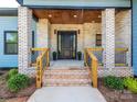 Welcoming front porch with brick pillars, wood accents, and a modern black front door at 2004 Plain Field Dr, Bessemer City, NC 28016