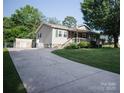 Home exterior showcasing a long driveway, partial stone facade, and complementary green shutters at 332 Daybrook Dr, Landis, NC 28088