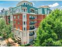 Luxury brick condominium building featuring a manicured entrance, multiple balconies, and lush landscaping at 401 N Church St # 201, Charlotte, NC 28202