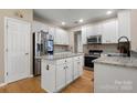 Well-lit kitchen features white cabinets, granite countertops, stainless steel appliances, and hardwood flooring at 4764 Brockton Nw Ct, Concord, NC 28027