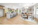 Open kitchen and dining space with modern light fixtures, an island, and hardwood floors throughout at 4929 Prentice Pl, Charlotte, NC 28210