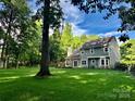 Exterior view of home's backyard showing large lawn, mature trees, and a spacious, fenced yard at 7344 Maitland Ln, Charlotte, NC 28215
