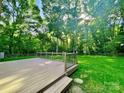 A wooden deck overlooks a well-manicured lawn surrounded by lush greenery and mature trees at 7344 Maitland Ln, Charlotte, NC 28215