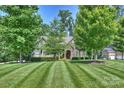 Beautiful lawn with meticulously cut grass and manicured trees leading to the stone facade home at 7916 Deerbridge St, Mint Hill, NC 28227
