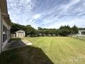 Large backyard featuring an outbuilding, a well-maintained lawn, and ample space for outdoor activities at 8429 Olde Stonegate Ln, Mint Hill, NC 28227