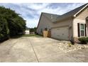 Spacious driveway leading to a two-car garage, complemented by manicured landscaping and side yard at 8429 Olde Stonegate Ln, Mint Hill, NC 28227