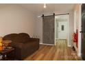 Inviting living room with wood flooring, cozy brown sofa, and stylish sliding barn door at 1028 Washburn Switch Rd, Shelby, NC 28150