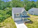 Aerial view of a light blue home, highlighting the landscaped yard, long driveway, and neighborhood at 1651 Carolina Cir, Gastonia, NC 28054