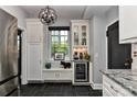 Well-appointed kitchen includes a wine refrigerator, granite countertops, custom cabinets, and black slate flooring at 301 W 10Th St # 404, Charlotte, NC 28202
