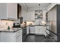 Modern kitchen with stainless steel appliances, black granite countertops, stylish white cabinets, and black slate flooring at 301 W 10Th St # 404, Charlotte, NC 28202