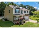 A two-story home with a welcoming front porch, stone accents, attached two-car garage, solar panels and a well-manicured lawn at 301 Wheat Field Dr, Mount Holly, NC 28120