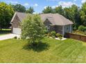 Rear view of the home showing brick exterior and backyard with mature tree at 3633 Longpond Ln, Monroe, NC 28110