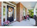 Charming covered porch featuring brick accents, a colorful wreath, and cozy seating at 4009 Oxford Mill Rd, Waxhaw, NC 28173