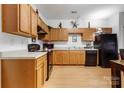 Open kitchen featuring oak cabinetry, black appliances, and laminate floors at 7138 Somerset Springs Dr, Charlotte, NC 28262