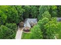 Aerial view of a brick home surrounded by lush green trees in a quiet neighborhood at 10501 Olde Irongate Ln, Mint Hill, NC 28227