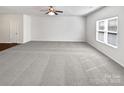 Spacious, carpeted living room with a ceiling fan and large window with blinds at 108 Greenway View Ct, Mount Holly, NC 28120