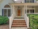 Inviting front porch with brick steps, ceiling fans and a stained wood front door at 12029 Forest Home Dr, Fort Mill, SC 29708