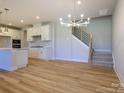 Open-concept kitchen with white cabinets, stainless steel appliances, and an adjacent staircase at 123 Armstrong Rd, Belmont, NC 28012