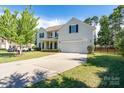 Traditional home with a manicured lawn, long driveway, and black shutters against a light yellow facade at 4003 Fine Robe Dr, Indian Trail, NC 28079