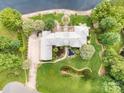 Aerial view of large brick estate home with lush, mature landscaping and private pond at 6823 Manatee Dr, Concord, NC 28025