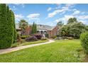 Charming brick home featuring lush landscaping, a decorative pond, and inviting walkway at 6823 Manatee Dr, Concord, NC 28025