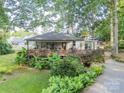 Spacious covered porch with lush landscaping and mature trees create a private outdoor living space at 7901 Bud Henderson Rd, Huntersville, NC 28078