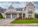 Beautiful stone-clad home with a three-car garage, lush lawn, and attractive landscaping at 13708 Huntson Park Ln, Huntersville, NC 28078