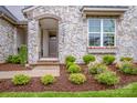 Charming stone front entrance with lovely landscaping and a window box brimming with flowers at 13708 Huntson Park Ln, Huntersville, NC 28078