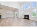 Bright, open-concept living room featuring a cozy fireplace, large windows, and light wood flooring at 18019 Wilbanks Dr, Charlotte, NC 28278