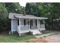 Cute gray home with white porch, black shutters, brick foundation, and a classic chimney at 2017 Ashley Rd, Charlotte, NC 28208