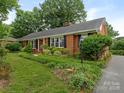 Brick ranch home featuring a beautifully landscaped front yard and a charming pathway at 3408 Oak Tree Trl, Matthews, NC 28105