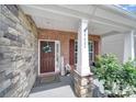 Inviting front porch with decorative wreath, welcome sign, and stone pillar accents at 5424 Tilley Manor Dr, Matthews, NC 28105
