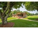 Beautiful brick home with a welcoming front porch, lush lawn, and mature trees in a serene setting at 5958 Hoover Elmore Rd, Lincolnton, NC 28092