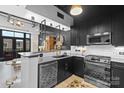Contemporary kitchen featuring stainless steel appliances, dark cabinets, and a stylish tile backsplash and decorative flooring at 720 Governor Morrison St # 219, Charlotte, NC 28211