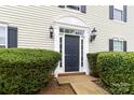 Elegant front door framed by sidelights and black sconces, surrounded by lush greenery at 1108 Plaza Walk Dr, Charlotte, NC 28215