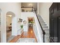 Grand foyer with hardwood floors, staircase, wainscoting, and a view to the dining room and hallway at 14203 Queens Carriage Pl, Charlotte, NC 28278