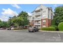 Apartment building with multiple balconies, brick facade, and ample parking space under a blue sky at 14347 San Paolo Ln, Charlotte, NC 28277