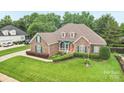 An elevated view of a brick house with green shutters, an orange door, and a well-maintained lawn at 1575 Williamsburg Dr, Rock Hill, SC 29732
