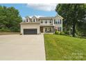 Charming brick home featuring dormer windows, attached garage, inviting front porch, and manicured lawn at 207 Spaniel Se Dr, Concord, NC 28025